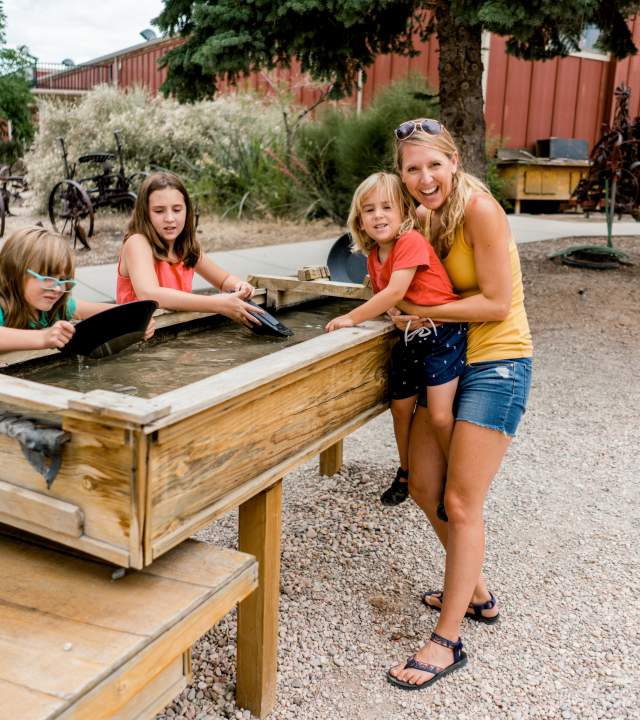 A mom and three kids pan for gold outside at the Frontier Homestead State Park Museum in Cedar City, Utah.