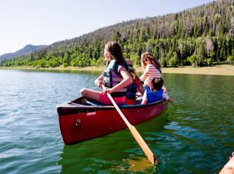 Family in a red canoe on the water of Navajo Lake, Utah.